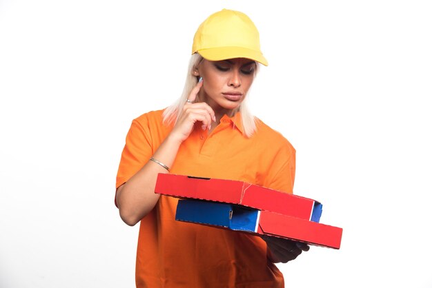 Mulher entregadora de pizza segurando pizza no fundo branco enquanto olha para eles. Foto de alta qualidade