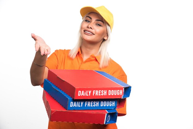 Mulher entregadora de pizza segurando pizza no fundo branco, mostrando a mão. Foto de alta qualidade