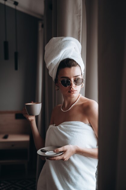 Mulher envolvida em uma toalha tomando café