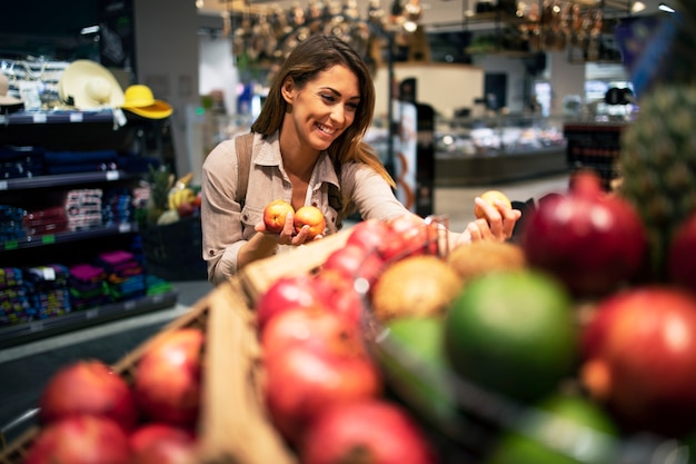 Mulher escolhendo cuidadosamente frutas para sua salada no supermercado