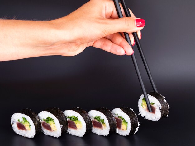 Mulher escolhendo um pedaço de rolo de sushi