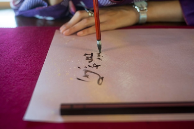 Mulher escrevendo com tinta em papel japonês
