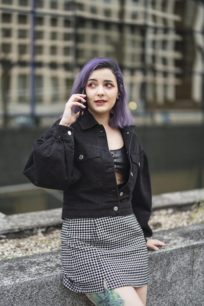 Mulher espanhola com cabelo roxo falando ao telefone