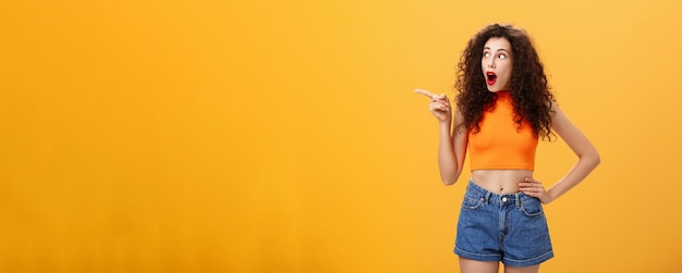 Foto grátis mulher espiando a janela do vizinho sendo surpreendida e espantada apontando e olhando sem palavras para a esquerda