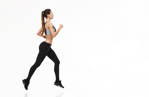 Foto grátis mulher esportiva no treinamento sportswear correndo em branco.