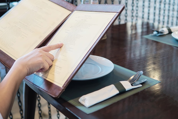 Mulher está escolhendo comida em um menu para pedir no restaurante