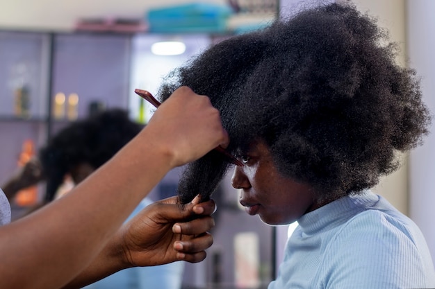 Mulher estilista cuidando do cabelo afro de seu cliente