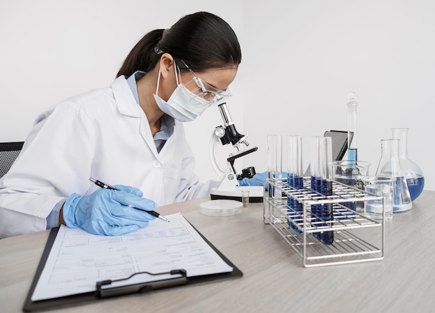 Foto grátis mulher estudando elementos químicos com um microscópio