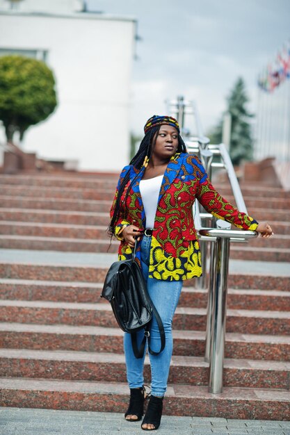 Mulher estudante africana posou com mochila no pátio da universidade contra bandeiras de diferentes países