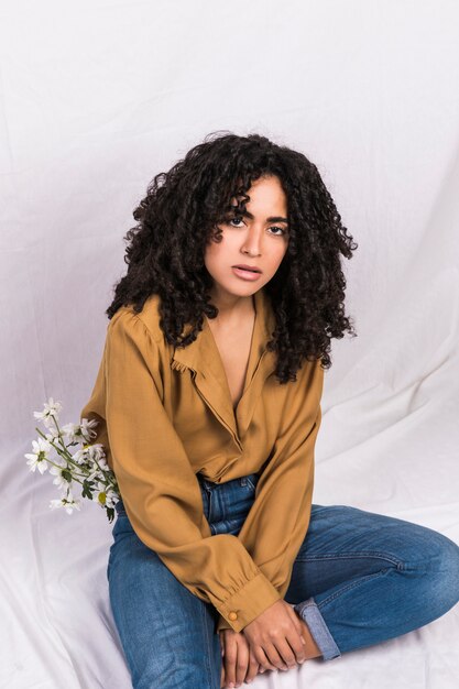 Mulher étnica elegante com flores em jeans