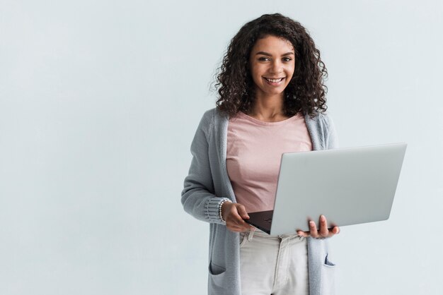 Mulher étnica sorridente com laptop cinza