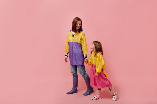 Mulher eu com menina criança bonita em capas de chuva. mãe filha pequena isolada