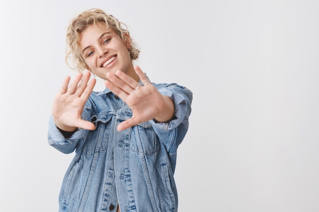 Mulher européia bonita, despreocupada e despreocupada vestindo jaqueta jeans, estique as mãos para a frente, encorajou muitos planos para o futuro sorrindo amplamente imaginando futuro perfeito aplicando o programa de universidade no exterior