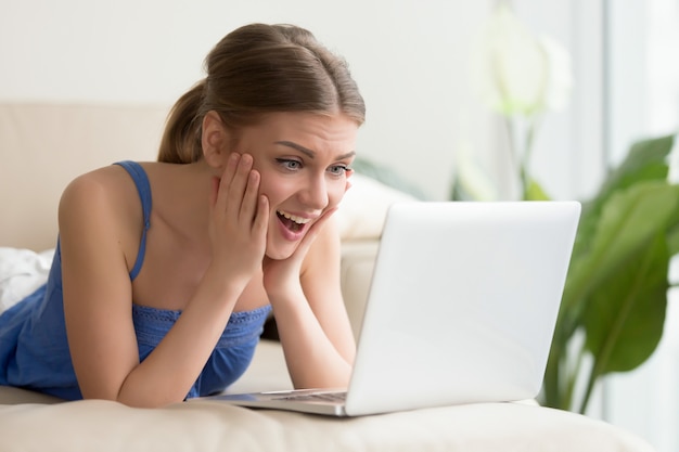 Mulher excitada assistindo filme engraçado no laptop