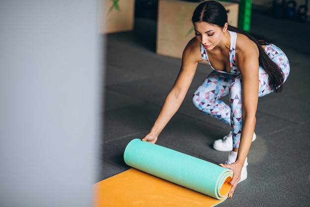Foto grátis mulher exercitando na academia segurando o tapete de ioga