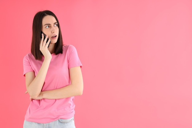 Mulher falando ao telefone em fundo rosa