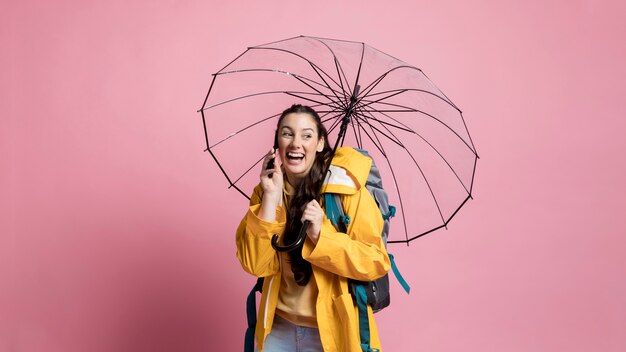 Mulher falando ao telefone, segurando um guarda-chuva