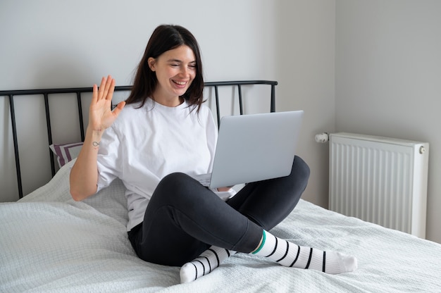 Mulher falando e usando seu laptop em casa durante a quarentena