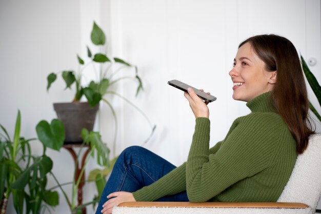 Mulher falando em seu smartphone enquanto está em casa usando o recurso viva-voz
