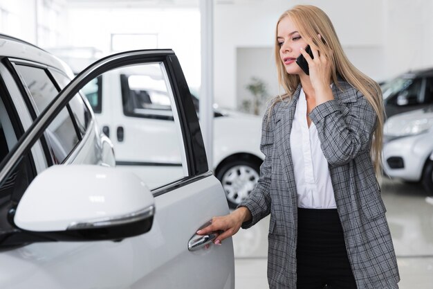 Mulher falando no telefone e abrindo a porta do carro