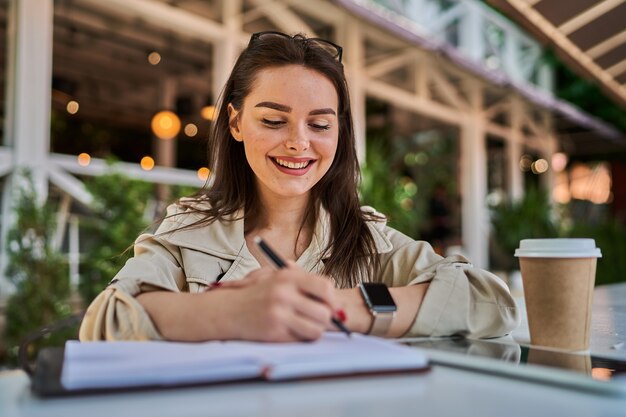 Mulher faz anotações no caderno na rua.