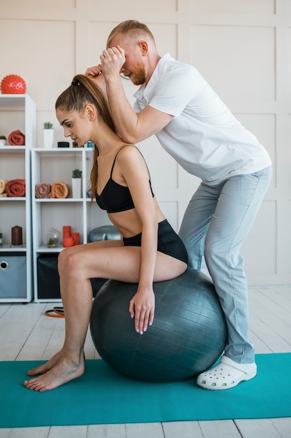 Foto grátis mulher fazendo exercícios com bola e fisioterapeuta