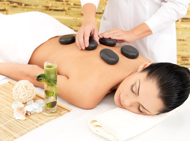 Mulher fazendo massagem com pedras quentes nas costas no salão de beleza