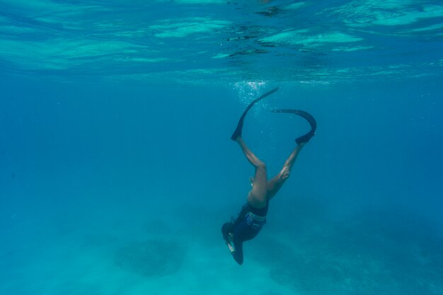 Mulher fazendo mergulho livre com nadadeiras debaixo d'água