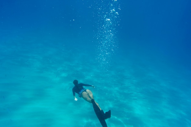 Mulher fazendo mergulho livre com nadadeiras debaixo d'água