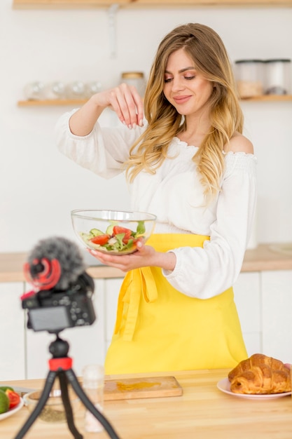 Mulher fazendo salada de legumes na câmera