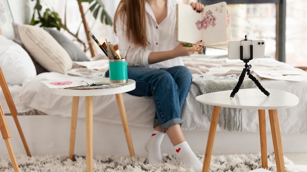 Mulher fazendo um tutorial de desenho com o telefone em casa