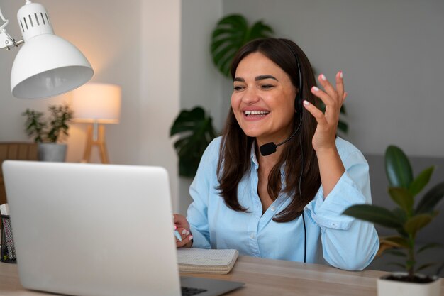 Mulher fazendo uma chamada de vídeo em casa em um laptop com fone de ouvido