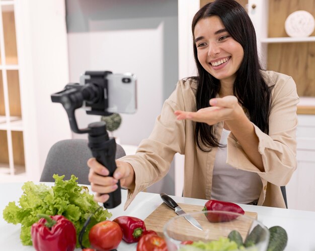 Mulher fazendo vlogs em casa com smartphone e vegetais