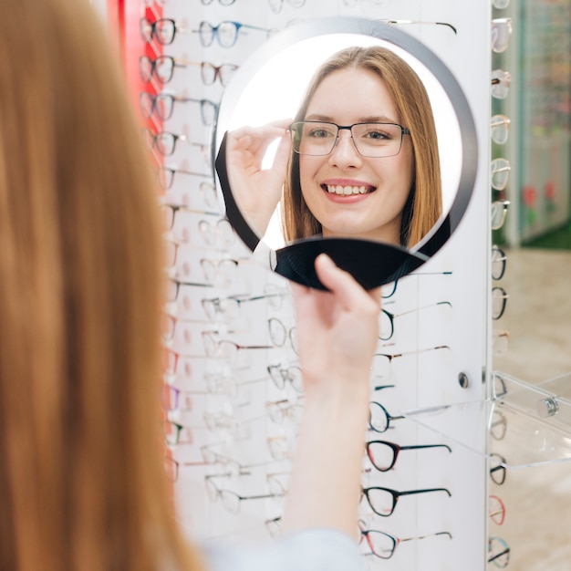 Mulher feliz à procura de novos óculos no optometrista