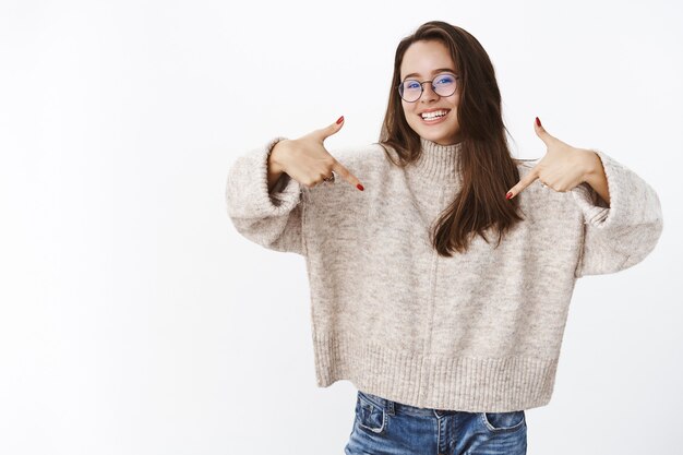 Mulher feliz carismática encantada de óculos apontando para si mesma