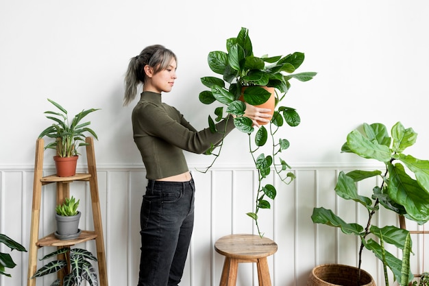 Foto grátis mulher feliz carregando uma planta de casa