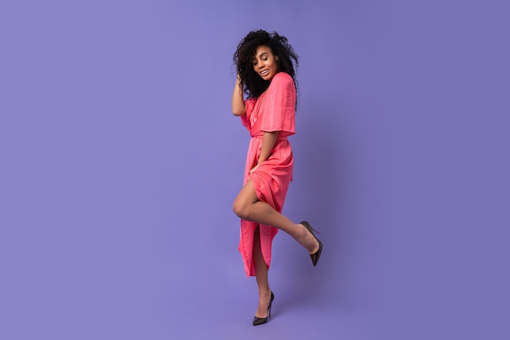Foto grátis mulher feliz com cabelos cacheados, posando sobre parede roxa. usando um elegante vestido de festa. look da moda primavera. toda a extensão.