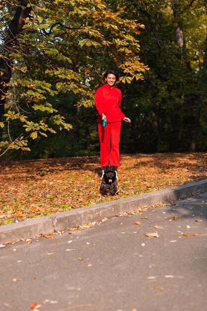 Mulher feliz com cachorro no parque com folhas outonais