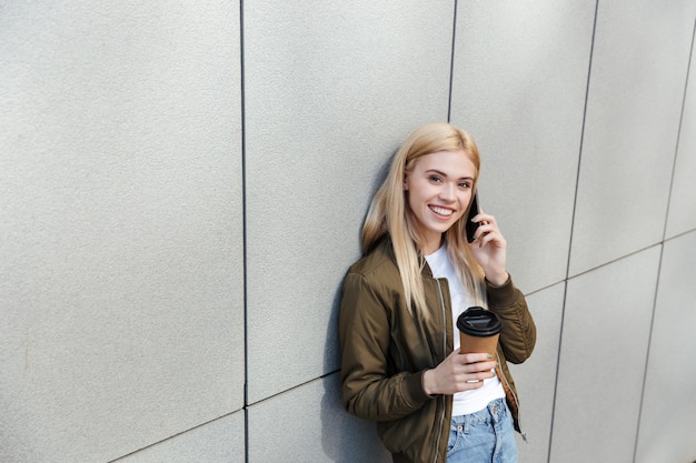 Mulher feliz com café falando no smartphone