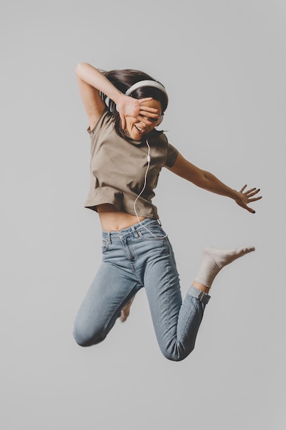 Foto grátis mulher feliz com fones de ouvido pulando no ar