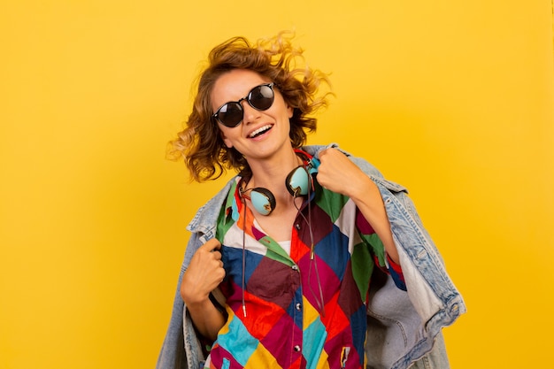 Foto grátis mulher feliz com penteado curto ouvindo música com fones de ouvido e se divertindo na parede amarela