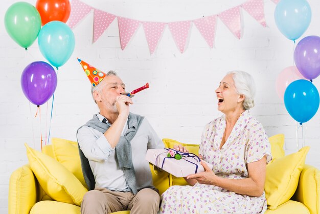 Mulher feliz, com, presente aniversário, olhar, dela, marido, soprando, partido, chifre