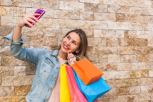 Mulher feliz com sacos de compras, tendo selfie