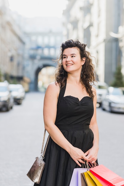 Foto grátis mulher feliz com sacos de papel em pé na rua