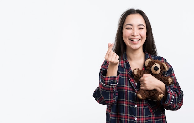 Mulher feliz com ursinho mostrando sinal de coração