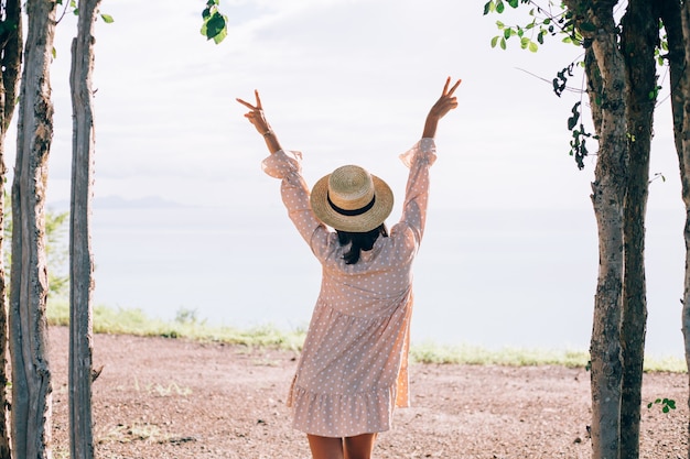 Mulher feliz com vestido fofo de verão e chapéu de palha nas férias com vistas tropicais exóticas