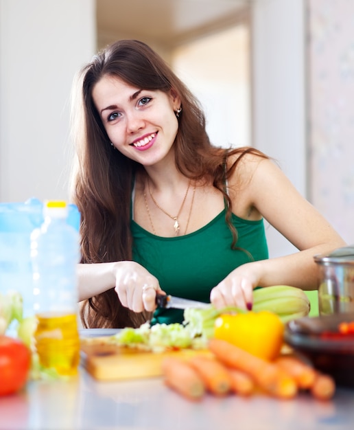 Mulher feliz cortando vegetais