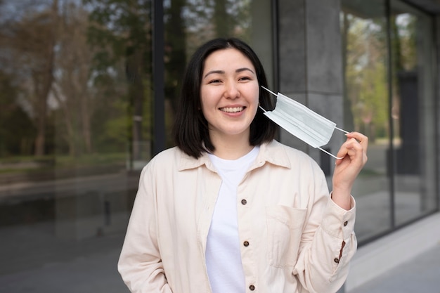 Foto grátis mulher feliz de tiro médio tirando a máscara facial