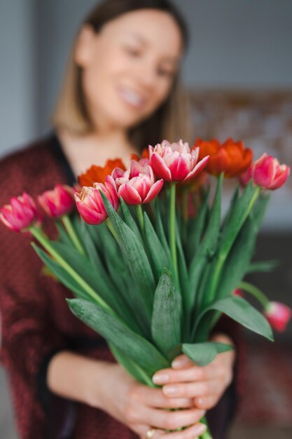 Mulher feliz desfruta de buquê de tulipas Dona de casa desfrutando de um monte de flores e interior da cozinha Doce lar Sem alergia