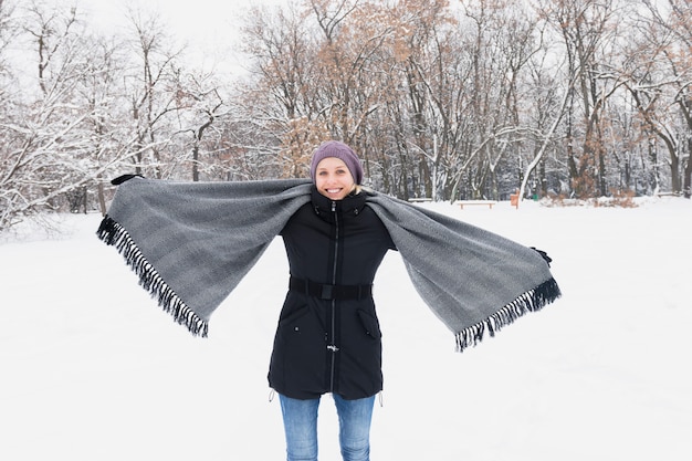 Mulher feliz, desgastar, roupa morna, e, segurando, cozy, echarpe, ficar, ligado, nevado, terra, em, inverno